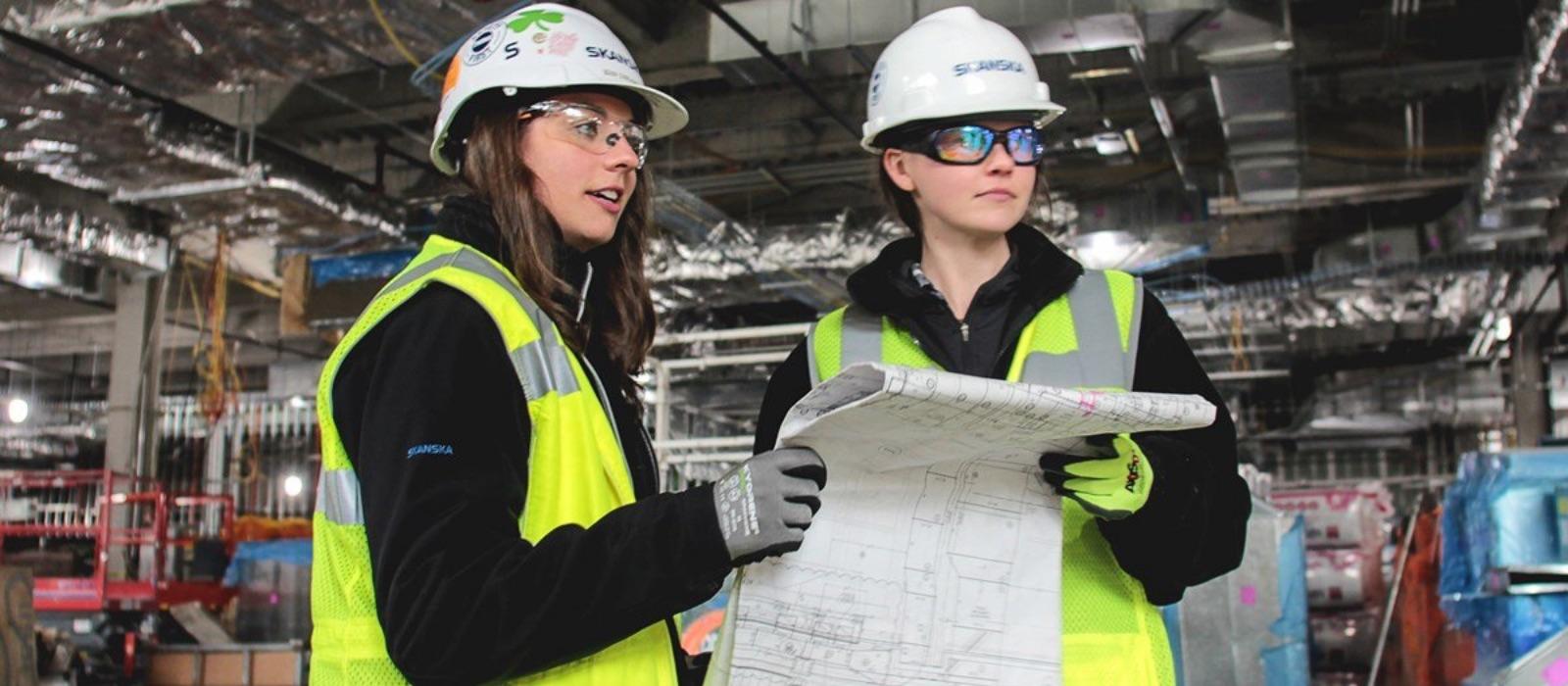 two female construction workers with blueprints